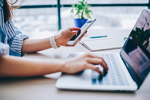 une personne qui travaille sur son ordinateur et son téléphone
