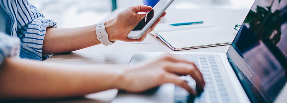 une personne qui travaille sur son ordinateur et téléphone